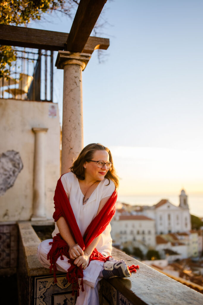 Karin, eine Persönlichkeit mit Charakter, sitzt bei Sonnenaufgang an einem Aussichtspunkt mit Blick über Lissabon :: photo copyright Karin Bergmann