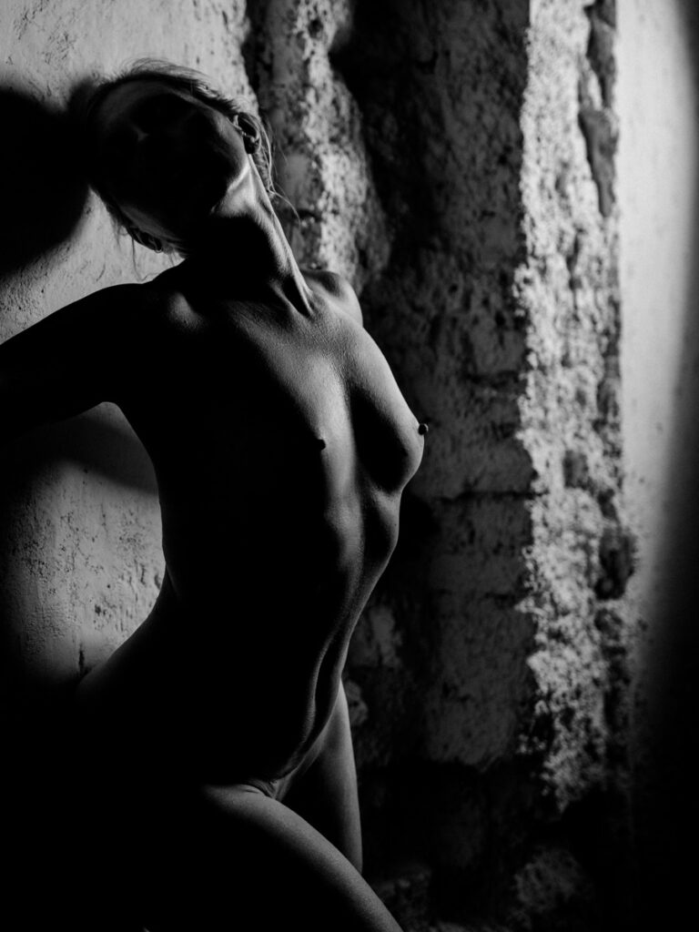 Boudoir in the style of nude photography, black and white, woman leaning against the wall and stretching with pleasure, detail with neck, ribcage and leg base :: photo copyright Karin Bergmann