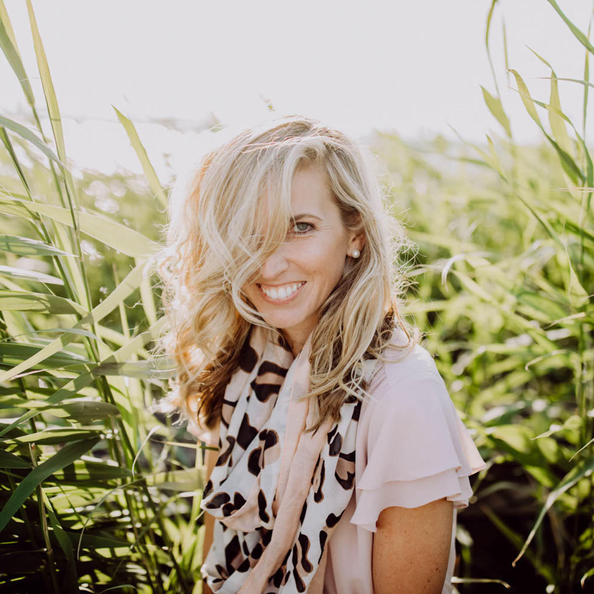 Lifestyle portrait photo, radiant smiling woman with blonde curls in the reeds on the lakeshore :: photo copyright Karin Bergmann
