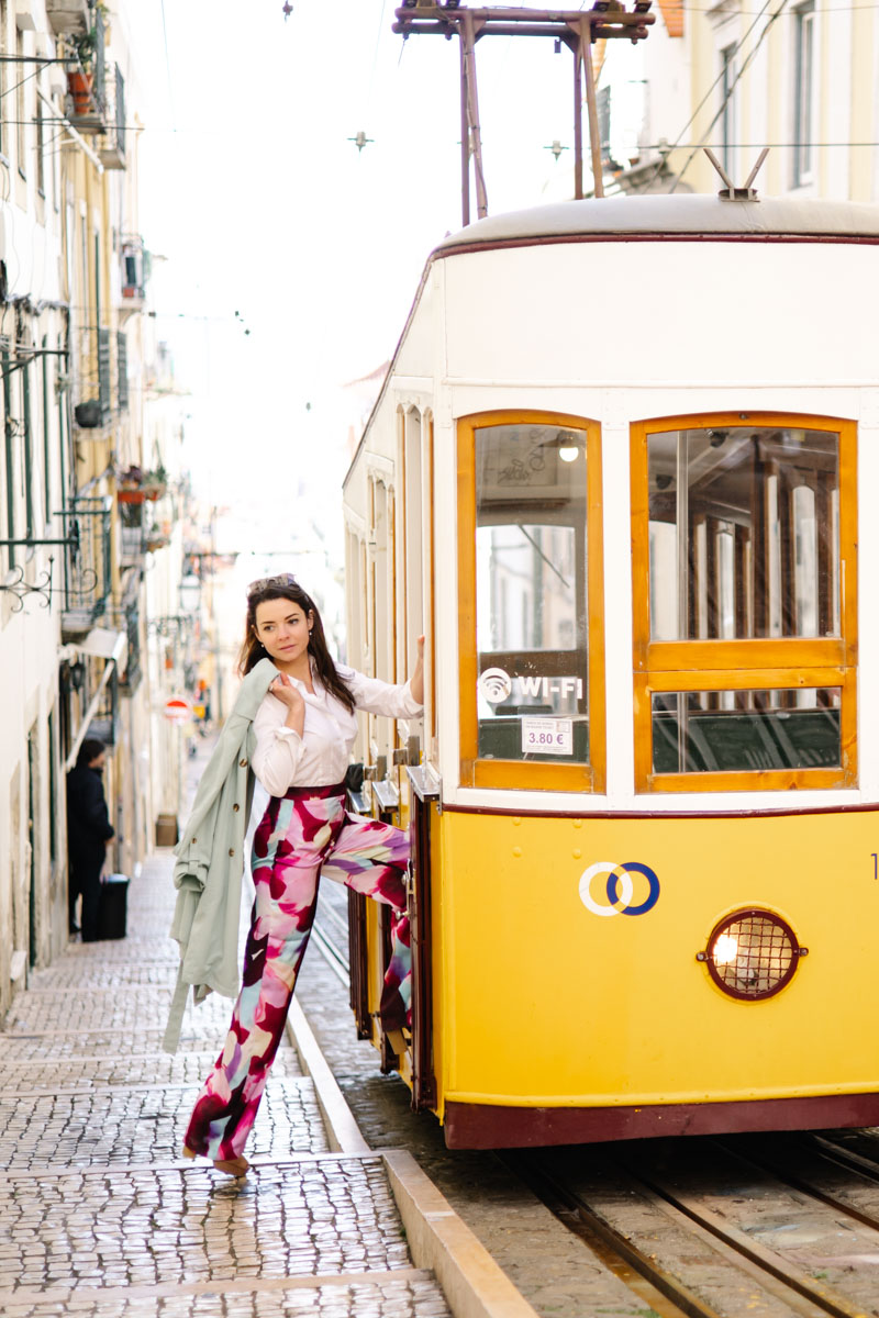 Lifestyle Portrait Foto, dynamische gut gekleidete Frau beim Einsteigen in eine typische gelbe Straßenbahn in Lissabon Portugal :: photo copyright Karin Bergmann