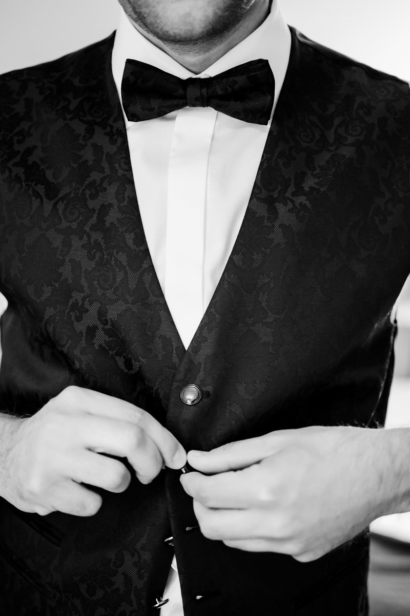 Wedding photo by wedding photographer, black and white, groom buttoning his gillet, close-up :: photo copyright Karin Bergmann