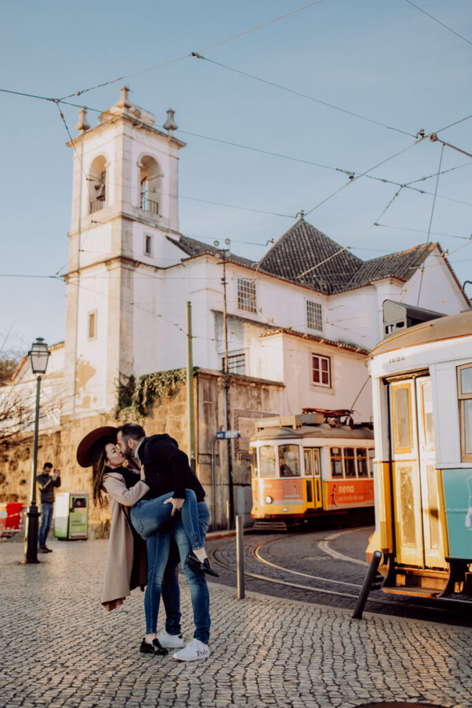 ausdruckstarkes Lifestyle Portrait Fotoshooting, ein Paar küsst innig, dahinter die typischen Straßenbahnen von Lissabon :: photo copyright Karin Bergmann