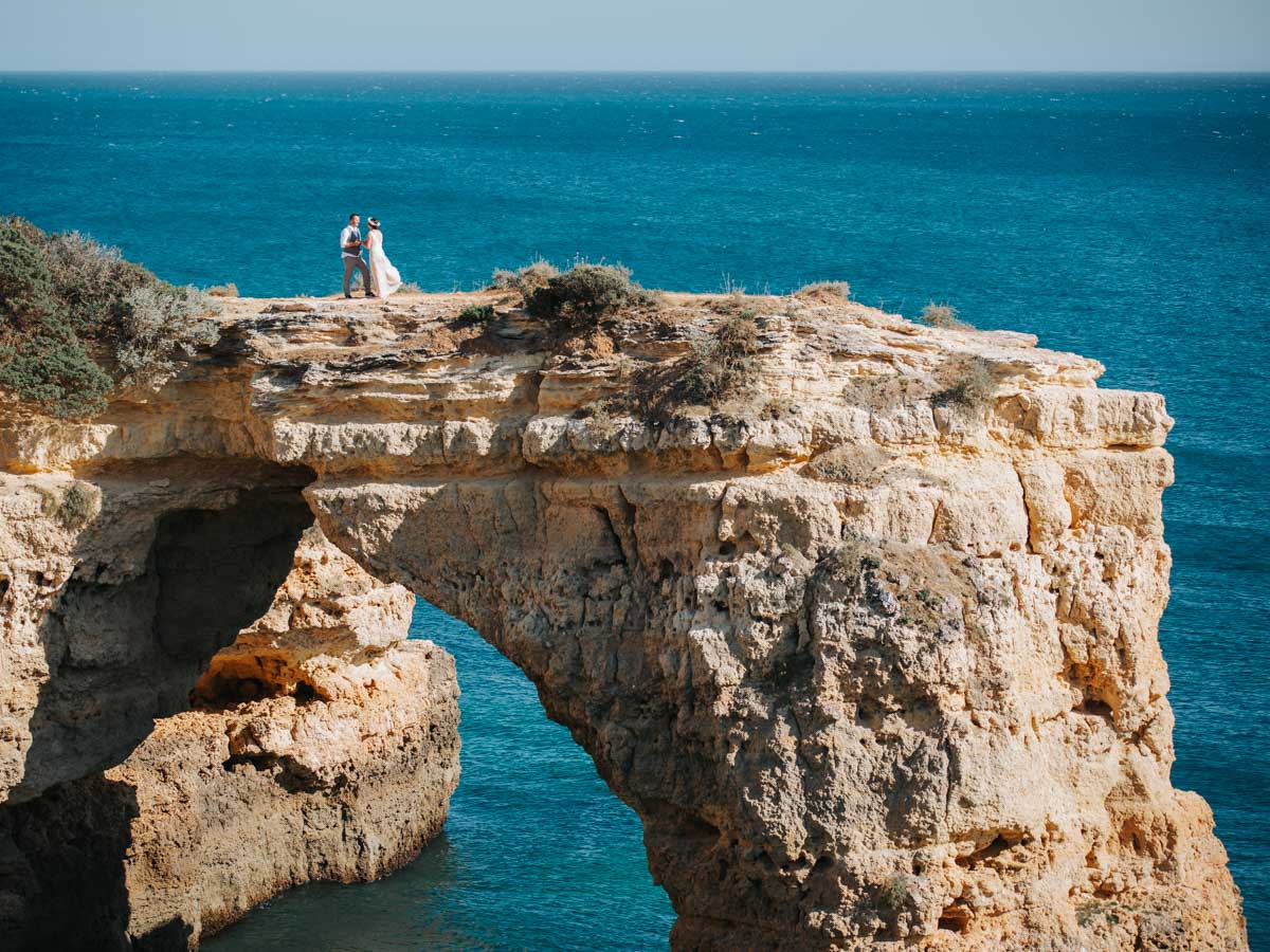 Lifestyle portrait, couple on a rocky bridge with impressive cliffs on the coast of the Algarve in Portugal :: photo copyright Karin Bergmann