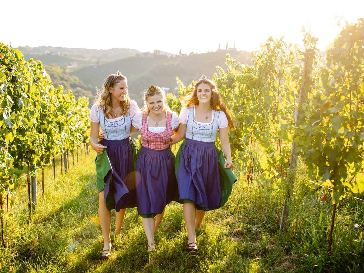 expressive lifestyle portrait photoshoot with three happy laughing friends in dirndls in a vineyard near Leibnitz :: photo copyright Karin Bergmann