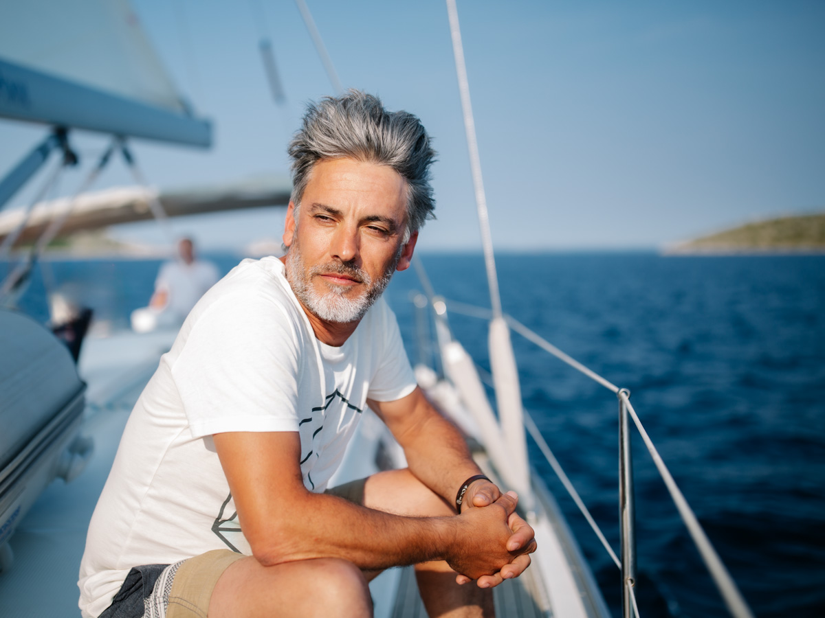 Lifestyle portrait, globetrotter sits on a sailing boat and looks calmly towards new adventures, somewhere on the sea between islands :: photo copyright Karin Bergmann
